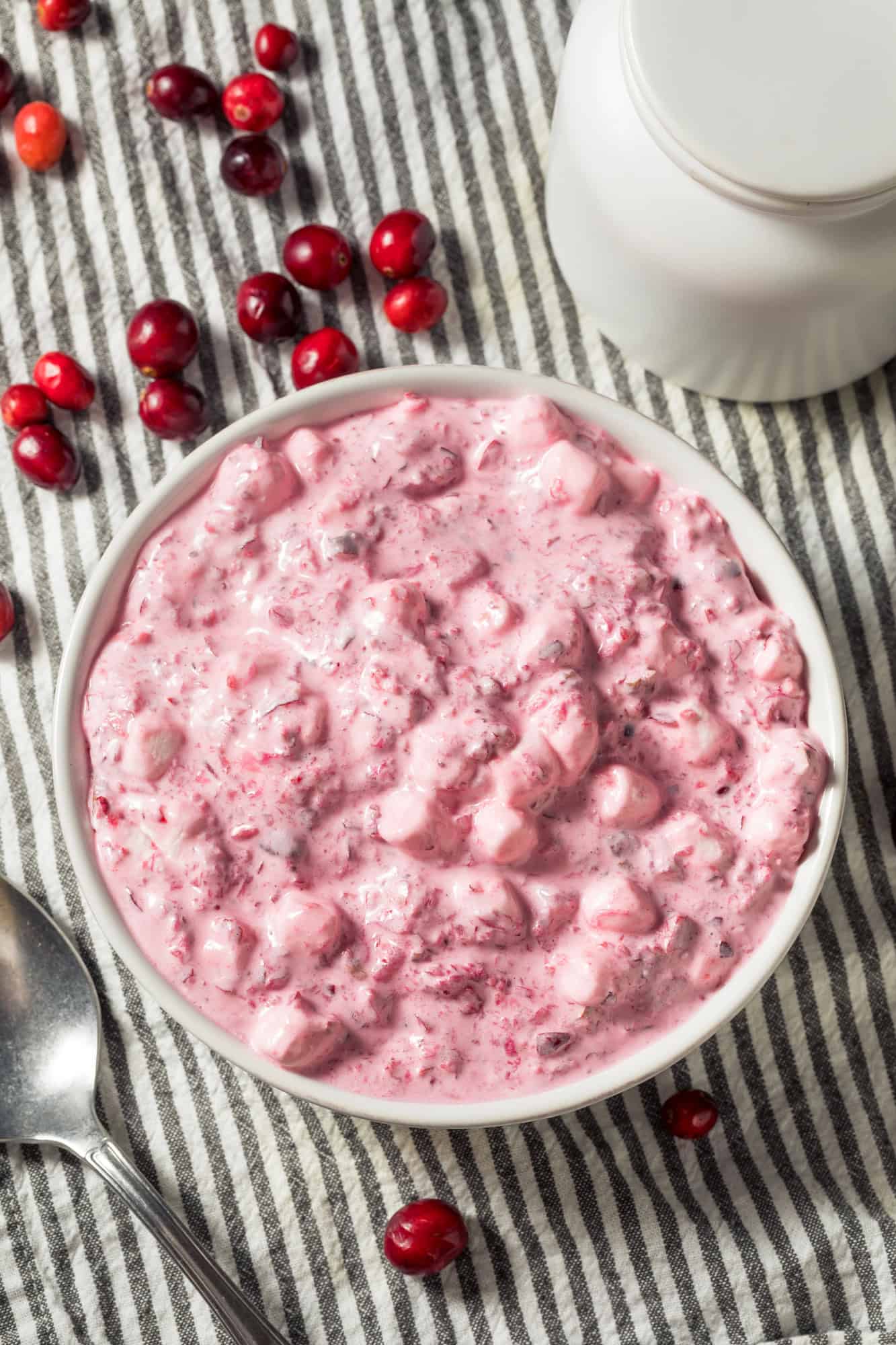 5 minute cranberry fluff salad with cool whip in a white bowl with whole cranberry garnishes
