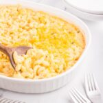 close up of old fashioned mac and cheese being spooned out of casserole dish