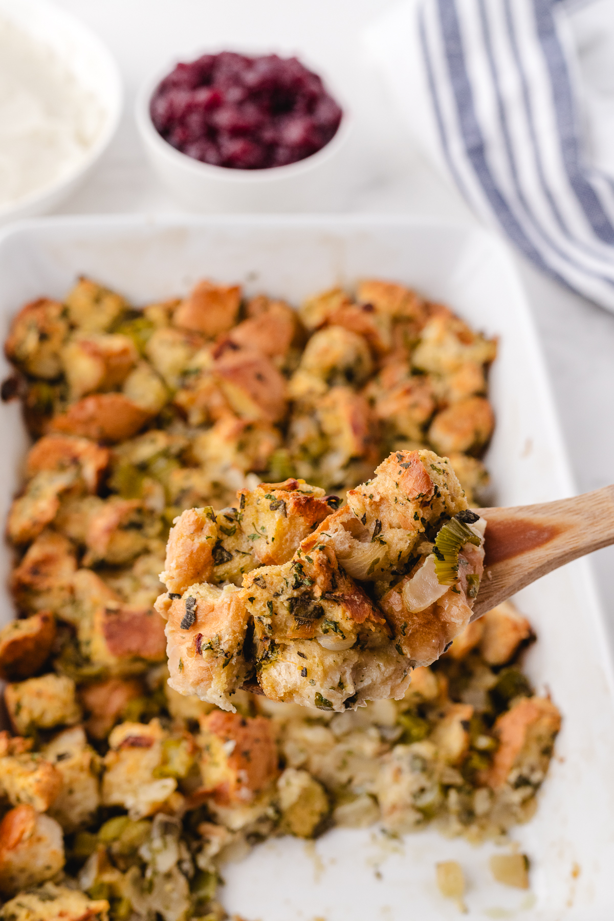 grandmas old fashioned  sage and onions stuffing in a 9x13 pan with a scoop on a wooden spoon