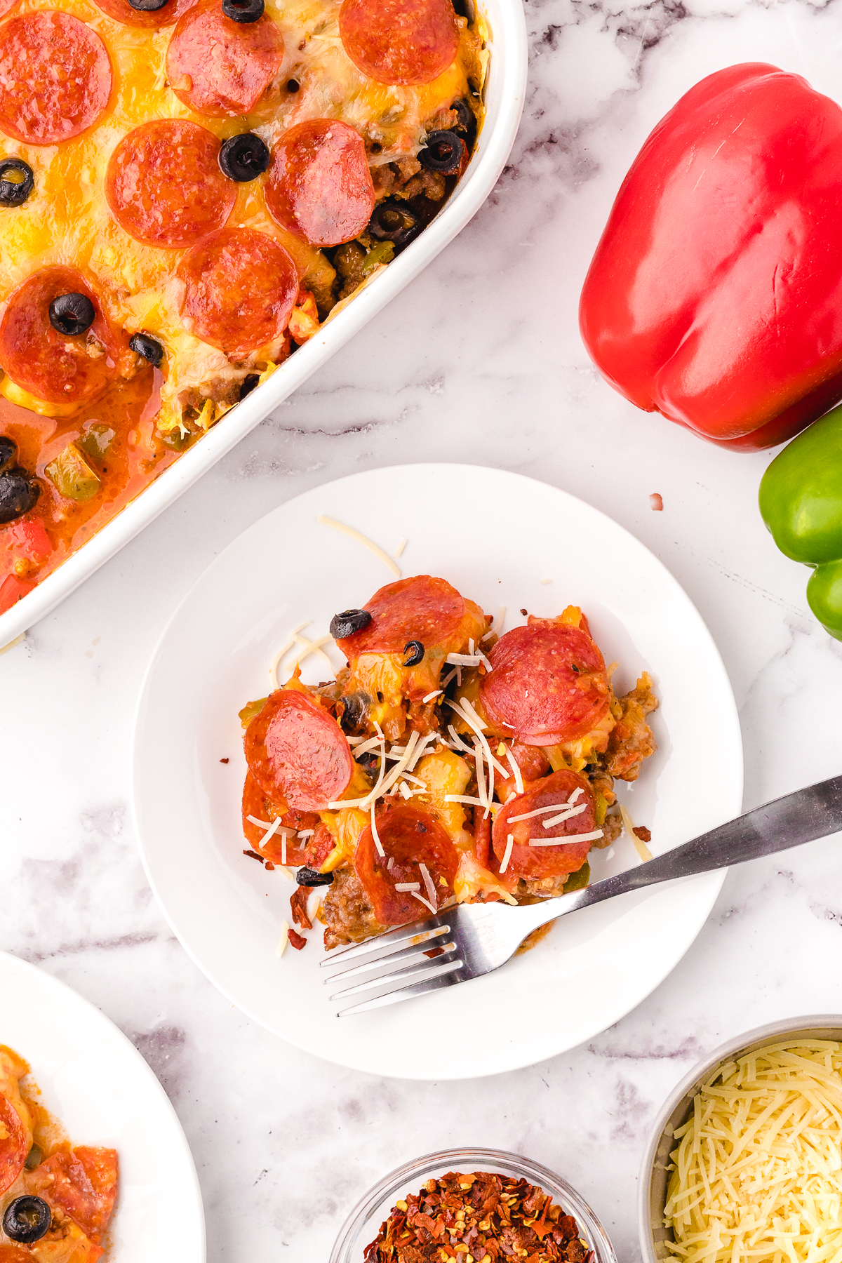 A plate of pizza casserole loaded with sausage, pepperoni, veggies, and cheese ready to eat.