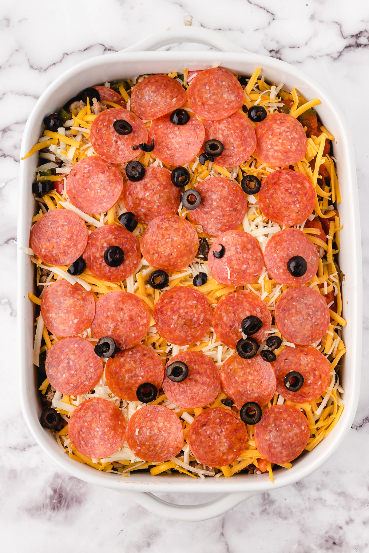 Old Fashioned Pizza Casserole assembled in a casserole dish before baking in the oven