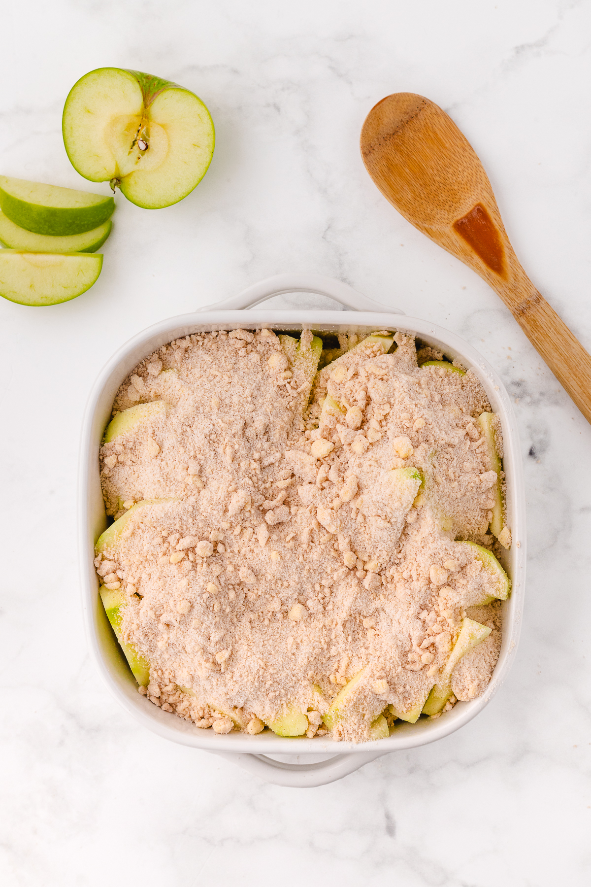 crispy green apples with the crumble topping over it getting ready to be baked