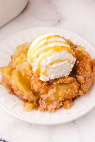Plate of old fashioned apple crisp topped with a scoop of ice cream sitting on a plate.