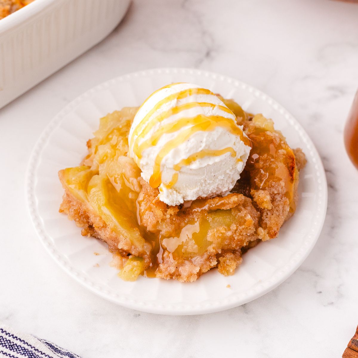 Plate of old fashioned apple crisp topped with a scoop of ice cream sitting on a plate.