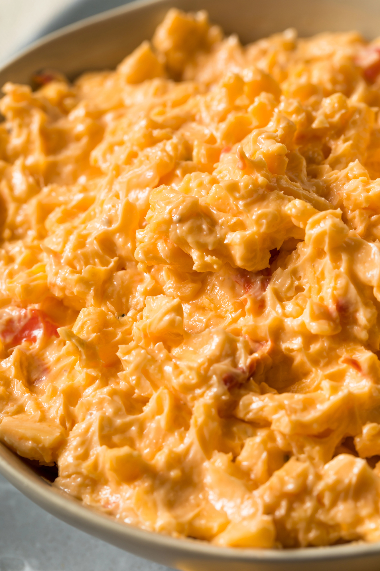 close up of old fashioned pimento cheese with mayo and shredded cheddar cheese with pimentos in a vintage  bowl