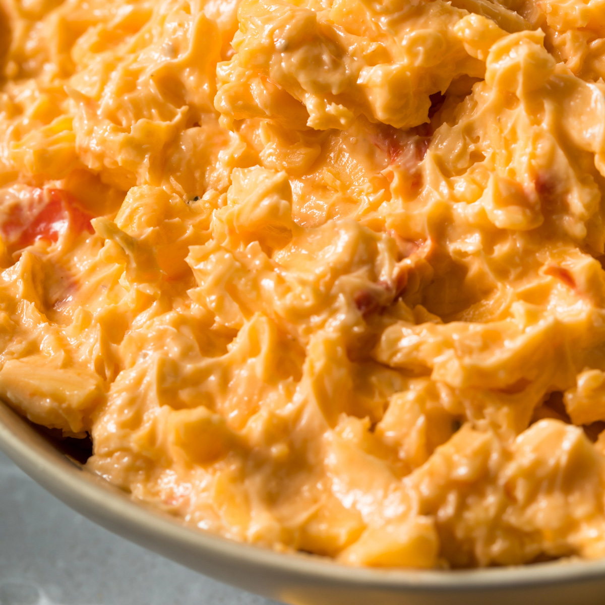 close up of grandmas pimento cheese recipe in a vintage green bowl with shredded sharp cheddar and Duke's mayo
