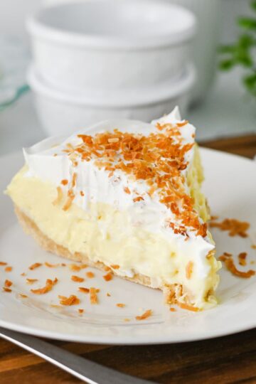 Slice of coconut cream pie on plate with fork.