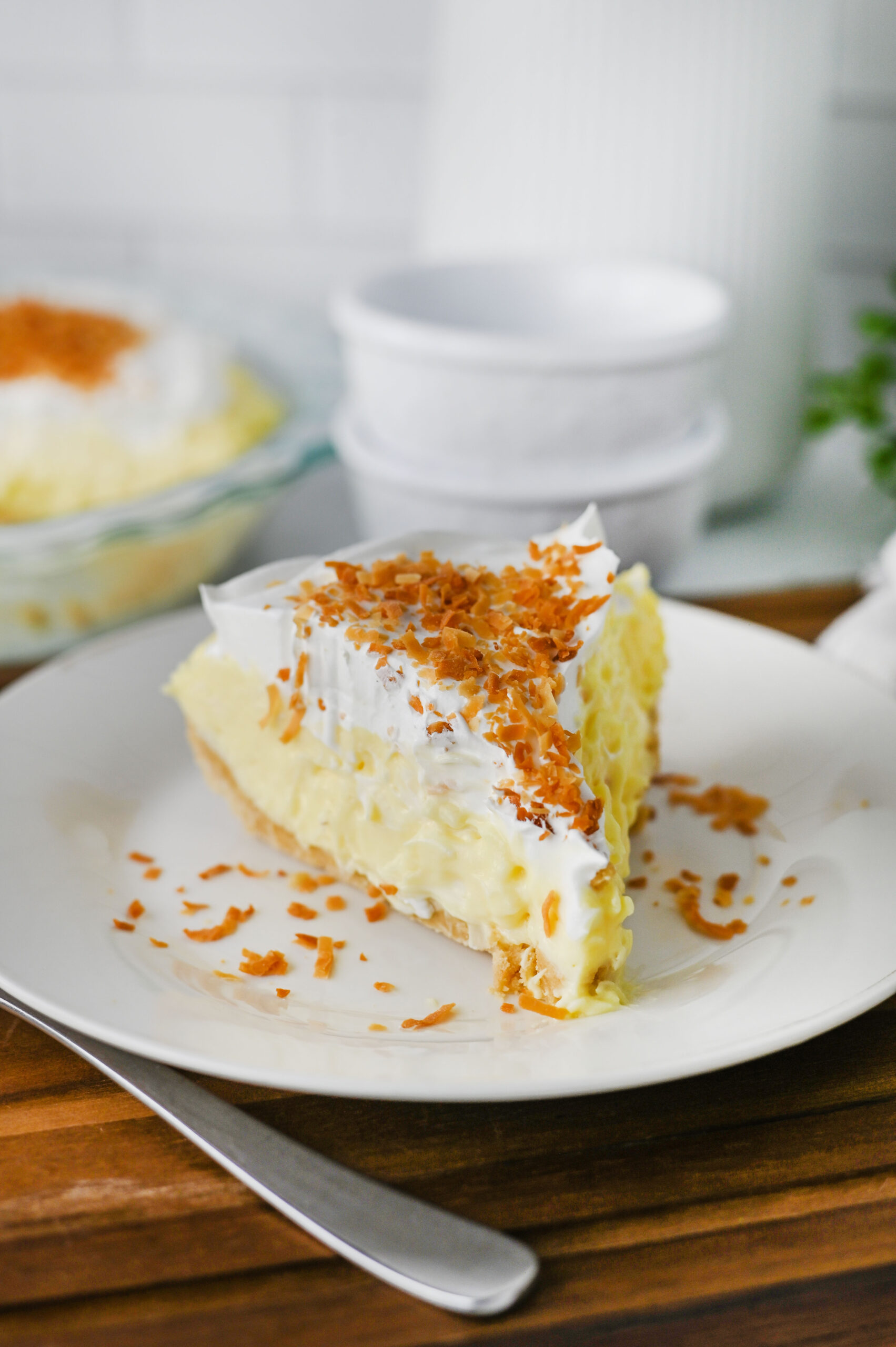 A slice of no bake coconut cream pie being served on a white plate.