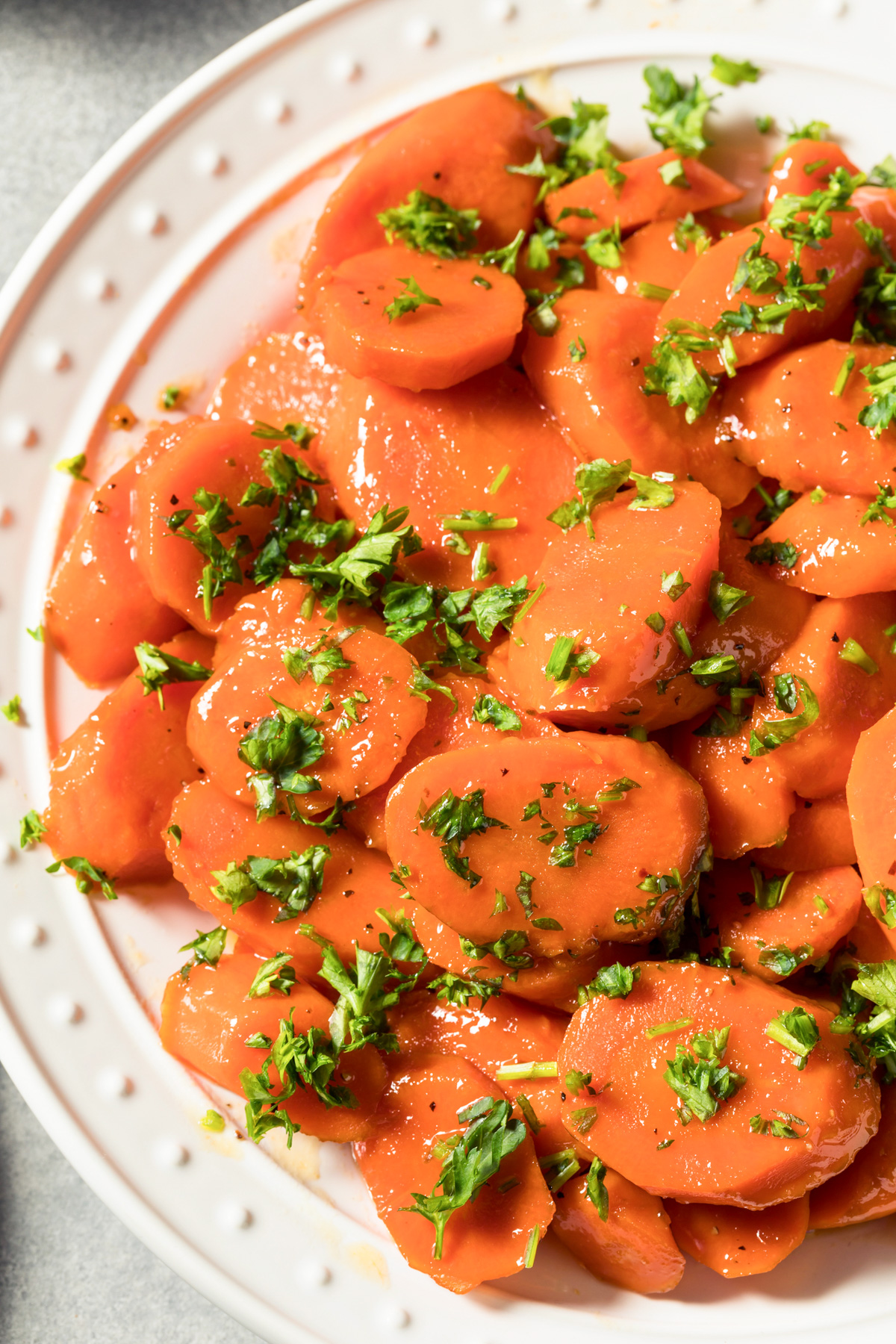 Sliced brown sugar glazed carrots with parsley on top.