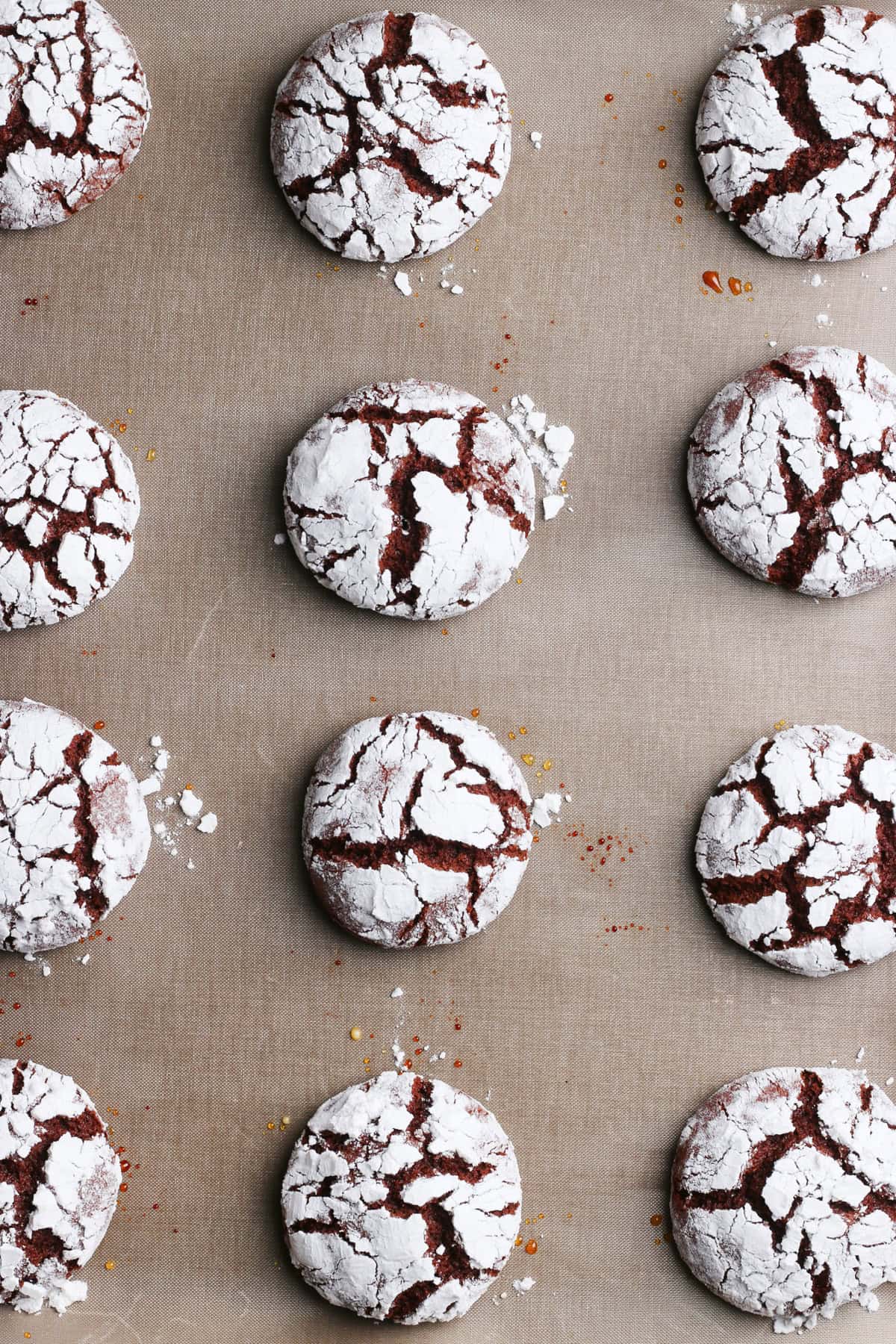 Chocolate crinkle cookies with powdered sugar tops on a baking mat
