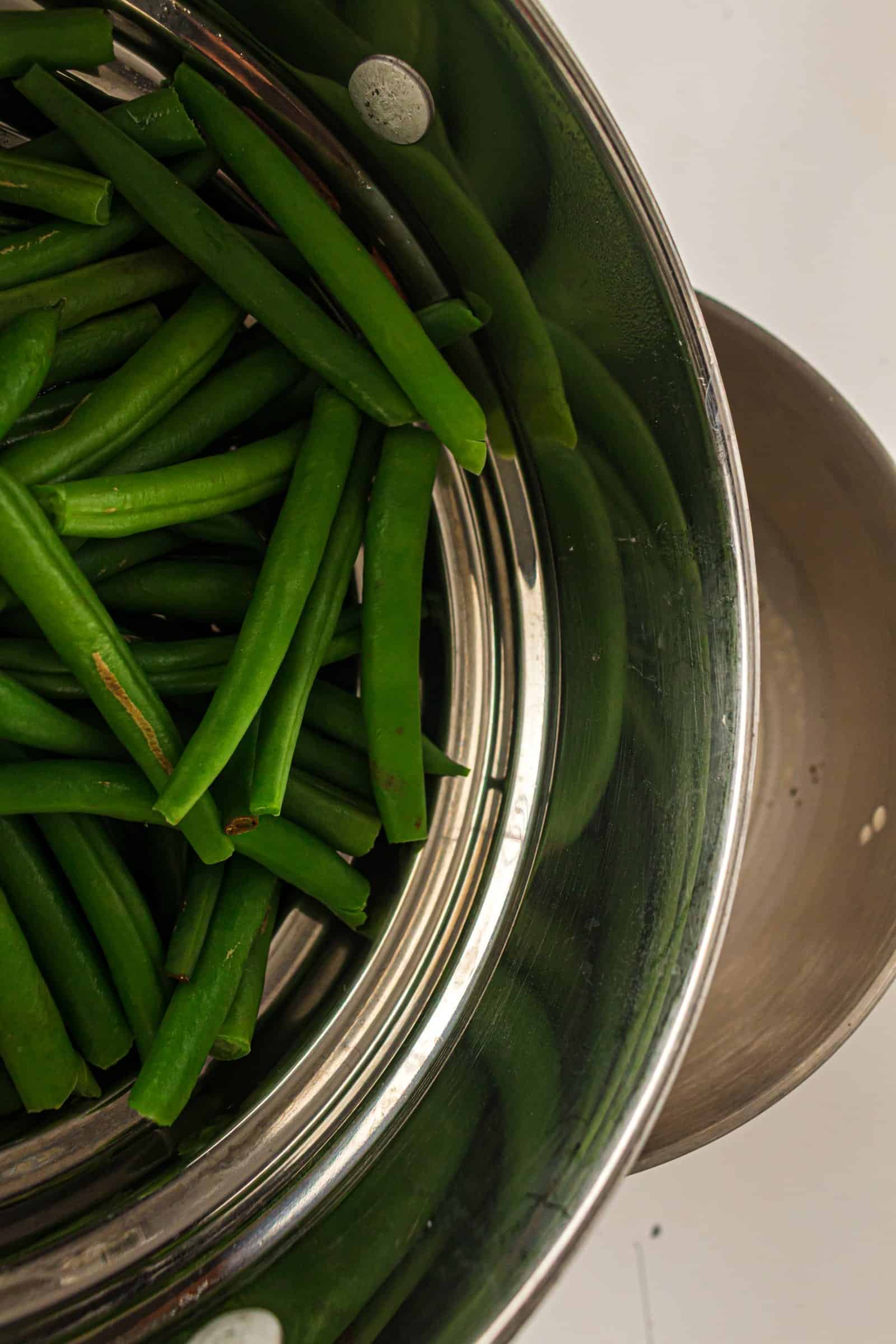 Green beans blanching in a large pot.