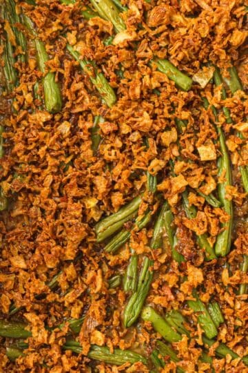 Green bean casserole with cream of mushroom soup topped with golden fried onions.