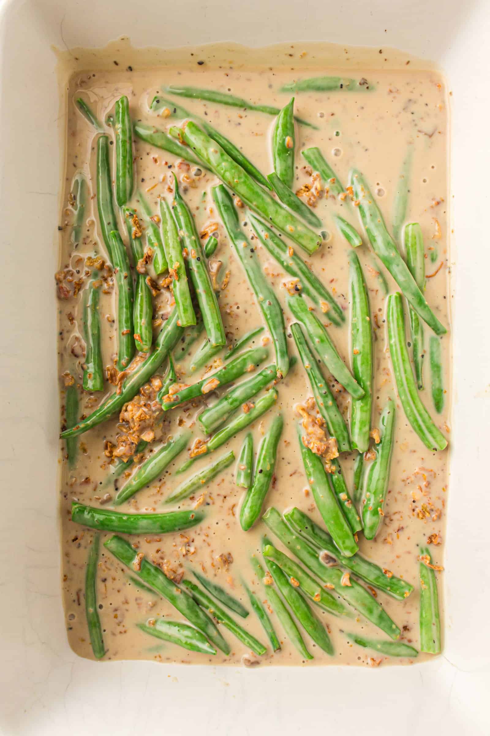 Green bean casserole spread in a baking dish before baking.