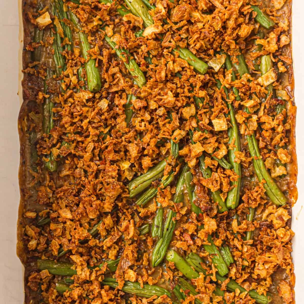 Green bean casserole with cream of mushroom soup topped with golden fried onions.