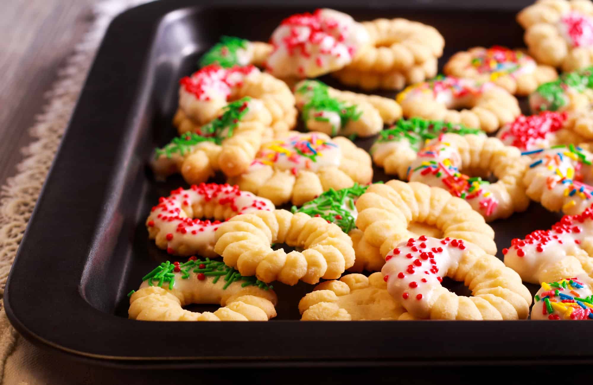 Close-up of spritz Christmas cookies dipped in icing with red and green sprinkles