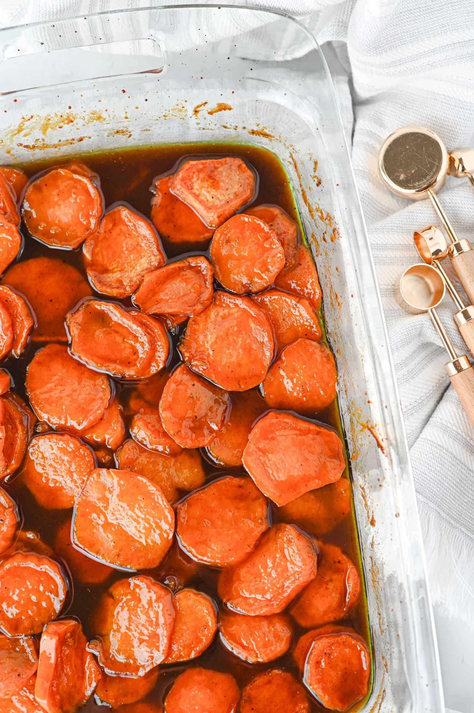 Old fashioned candied sweet potatoes in a glass baking dish with brown sugar syrup.
