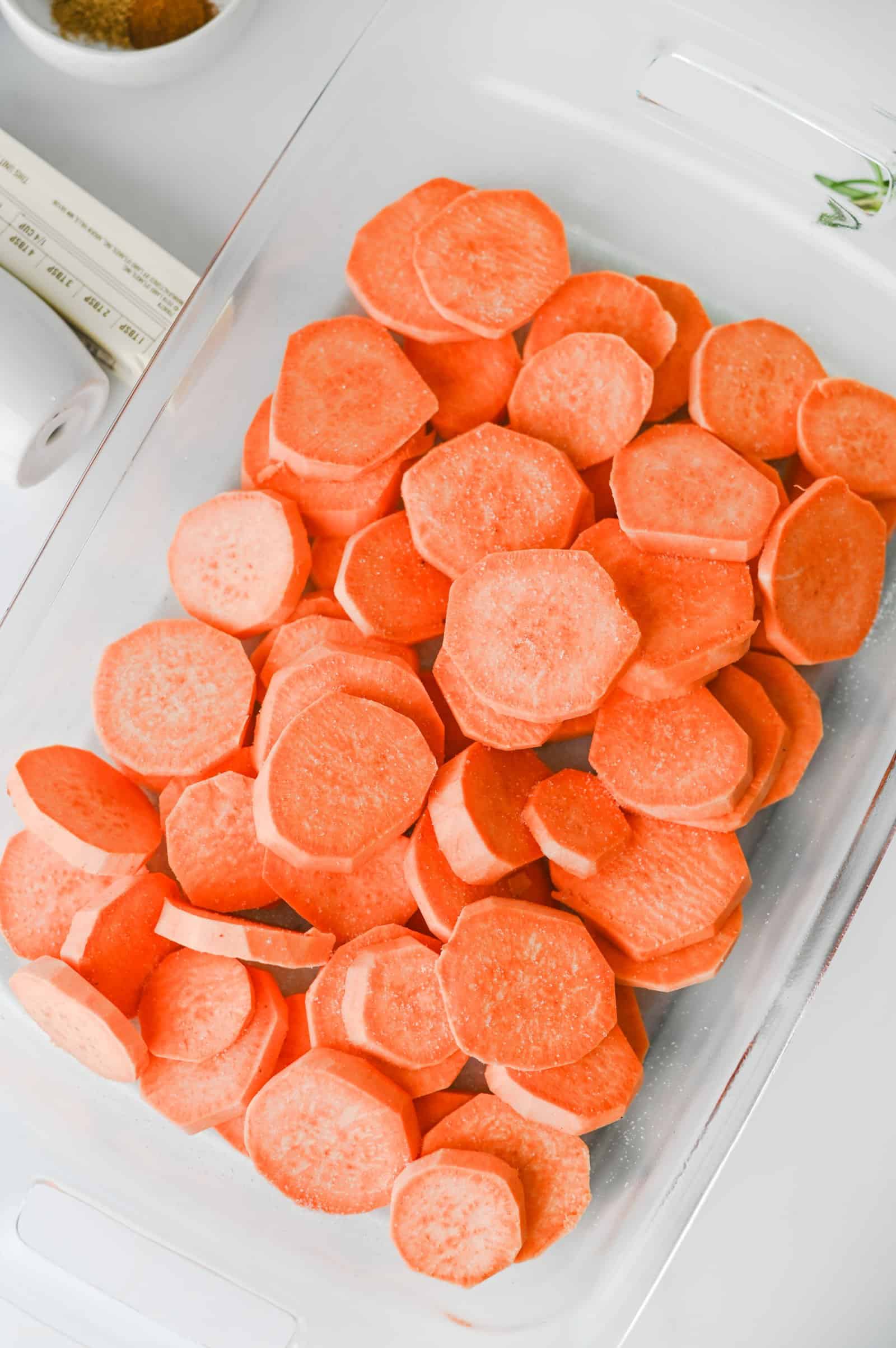 Sliced sweet potatoes spread in a baking dish.