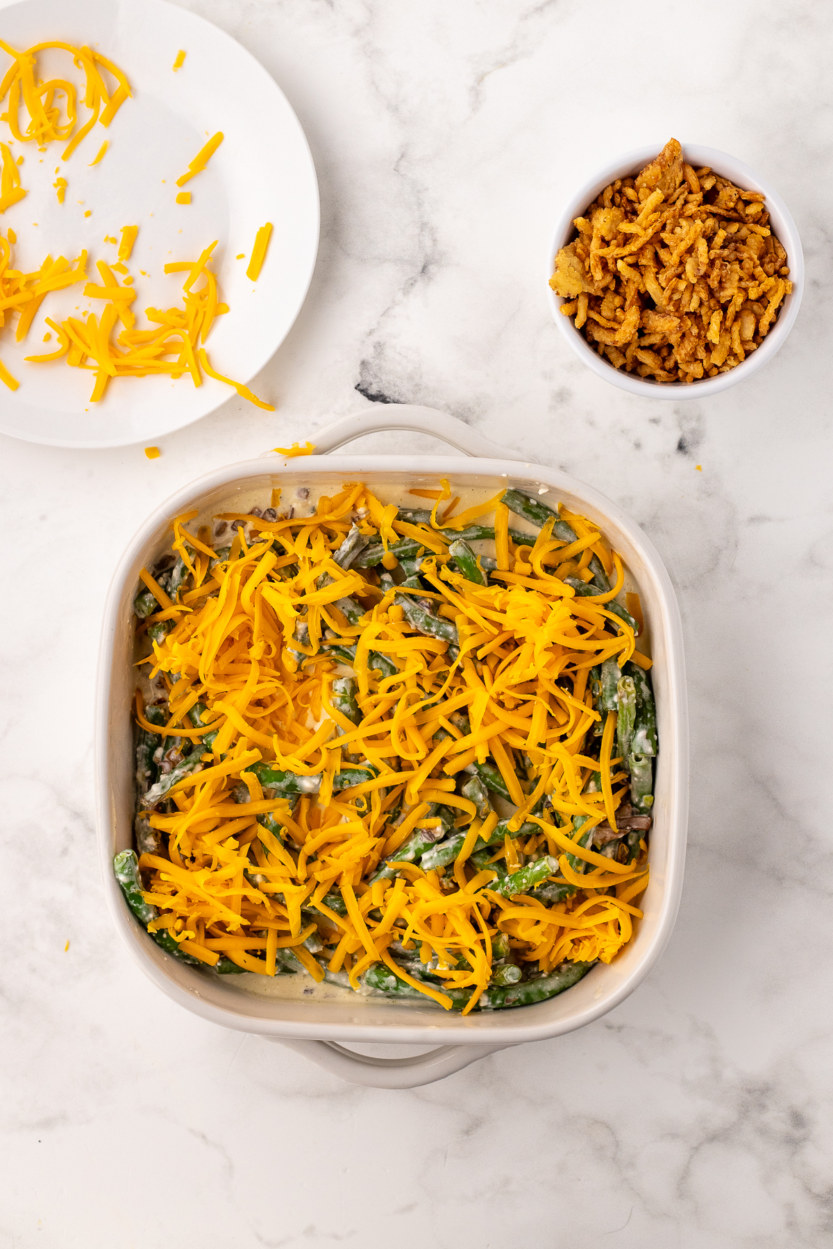 putting the casserole into a dish and topping it with cheese