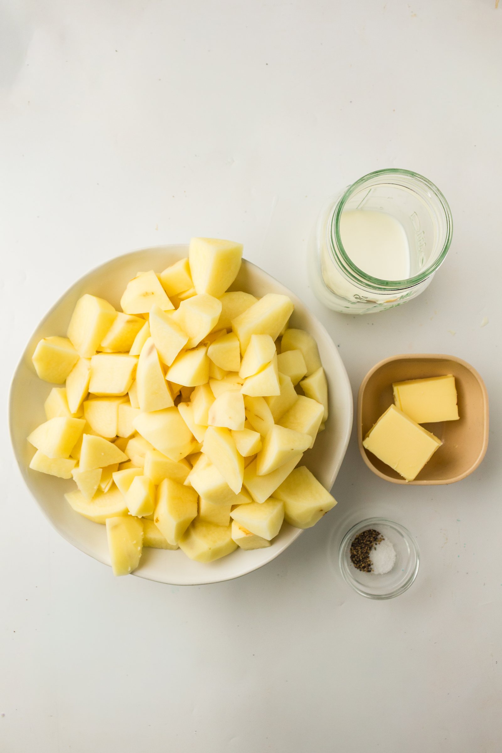 Ingredients for old fashioned mashed potatoes: cubed potatoes, butter, cream, salt and pepper.