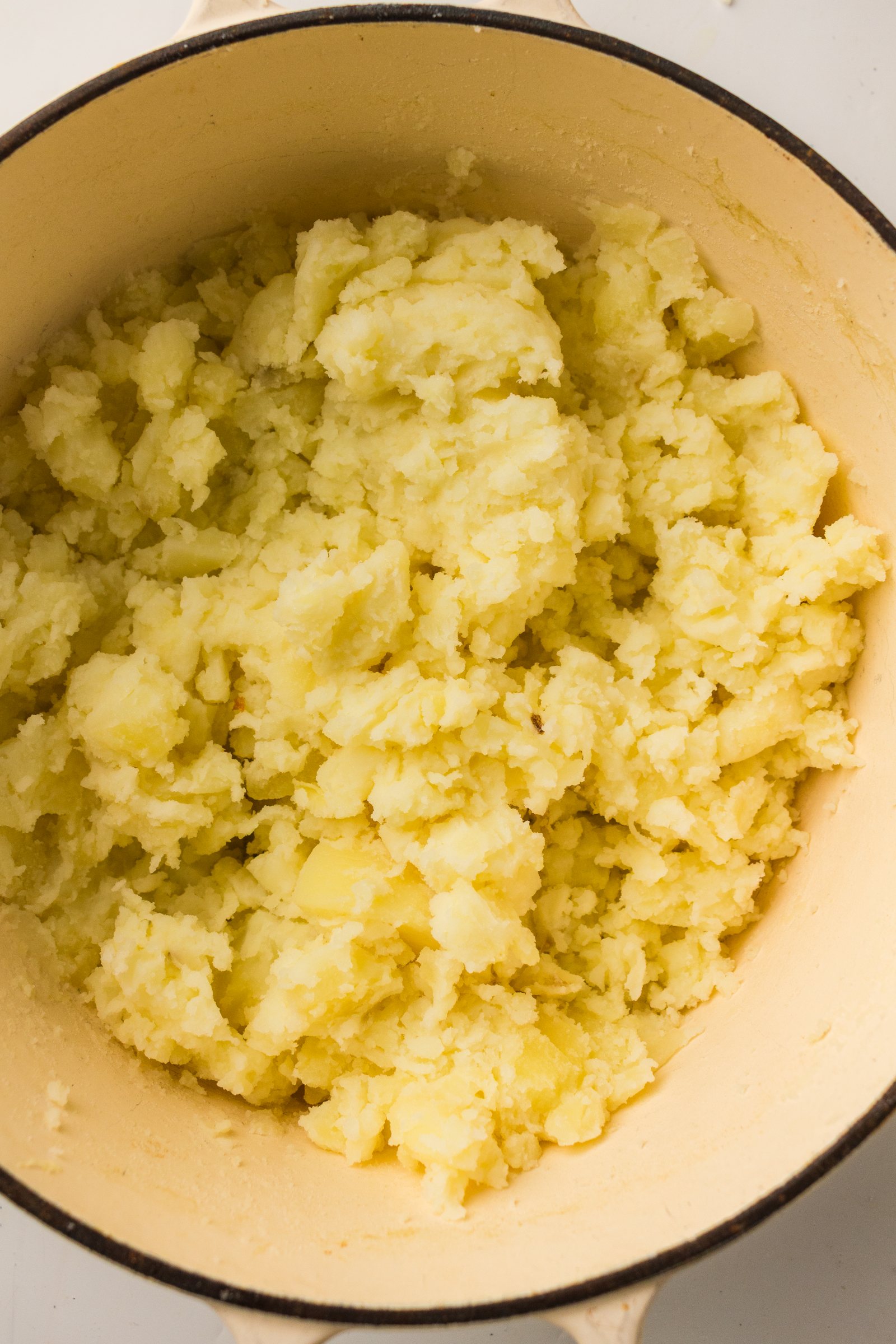 Potatoes mashed by hand in the pot.