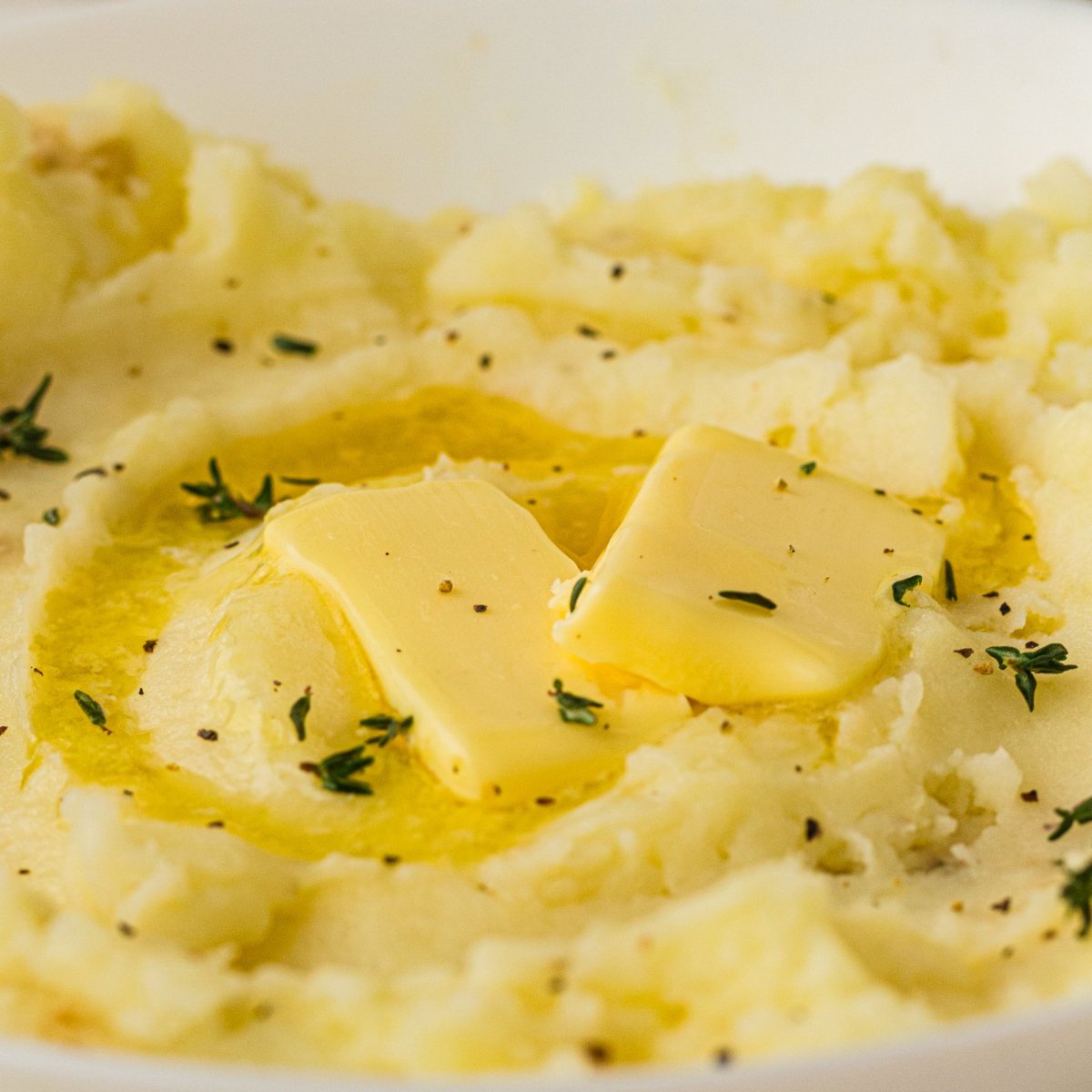Old fashioned mashed potatoes topped with melting butter and fresh thyme.
