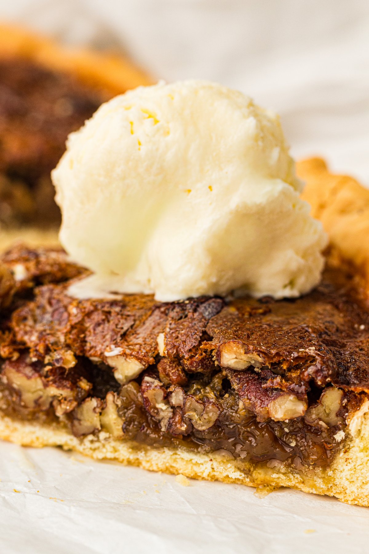 Slice of old fashioned pecan pie topped with a scoop of vanilla ice cream.