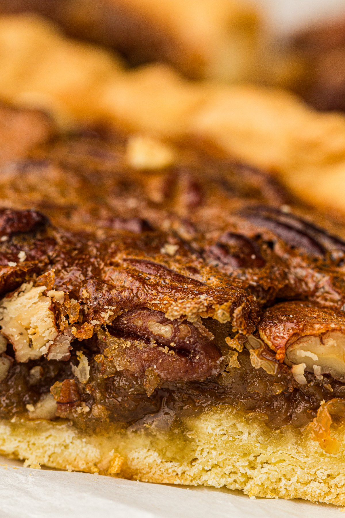 Close-up of a slice of old fashioned pecan pie with a gooey brown sugar filling and flaky crust.