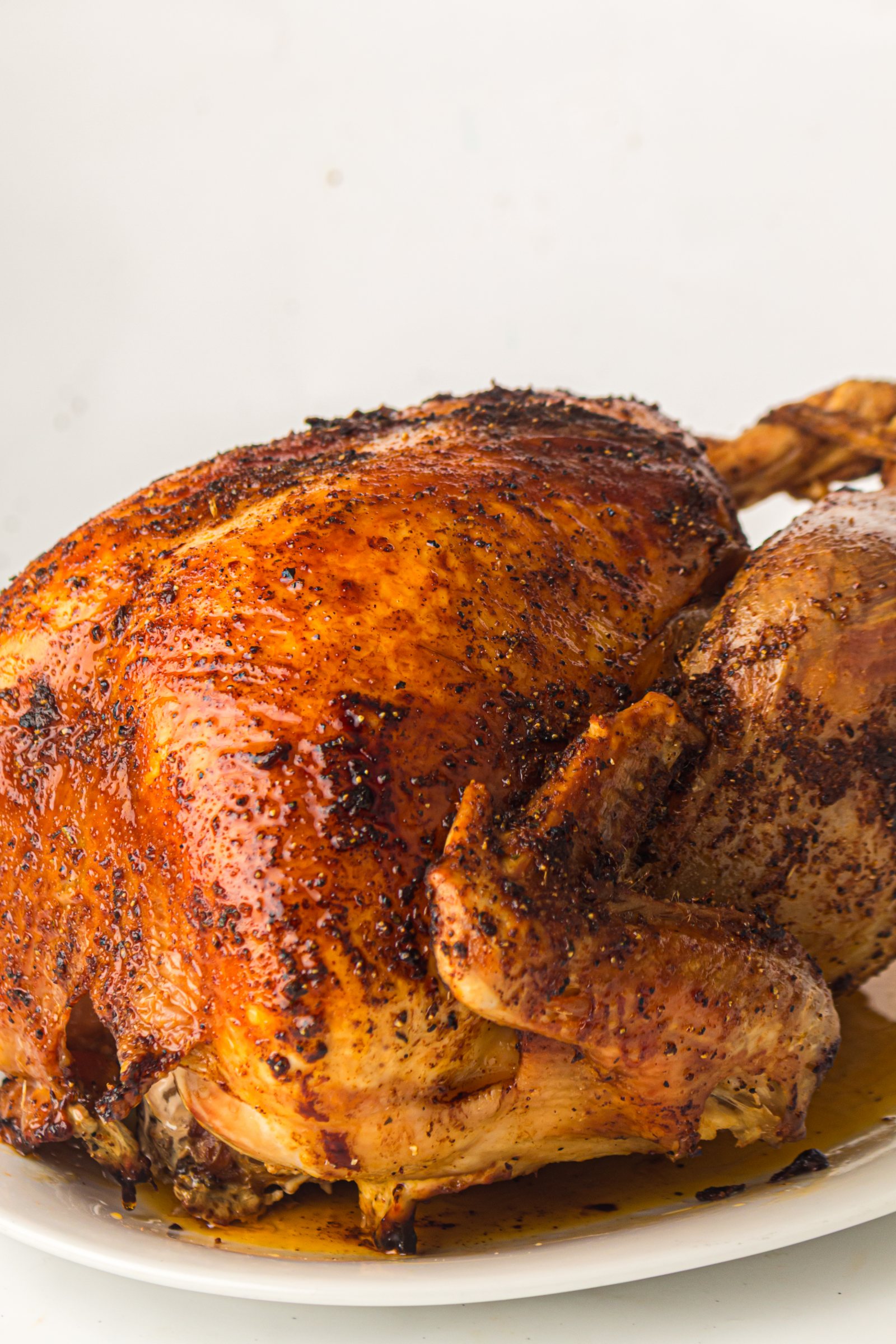 Golden roast turkey with butter under the skin on a white platter.