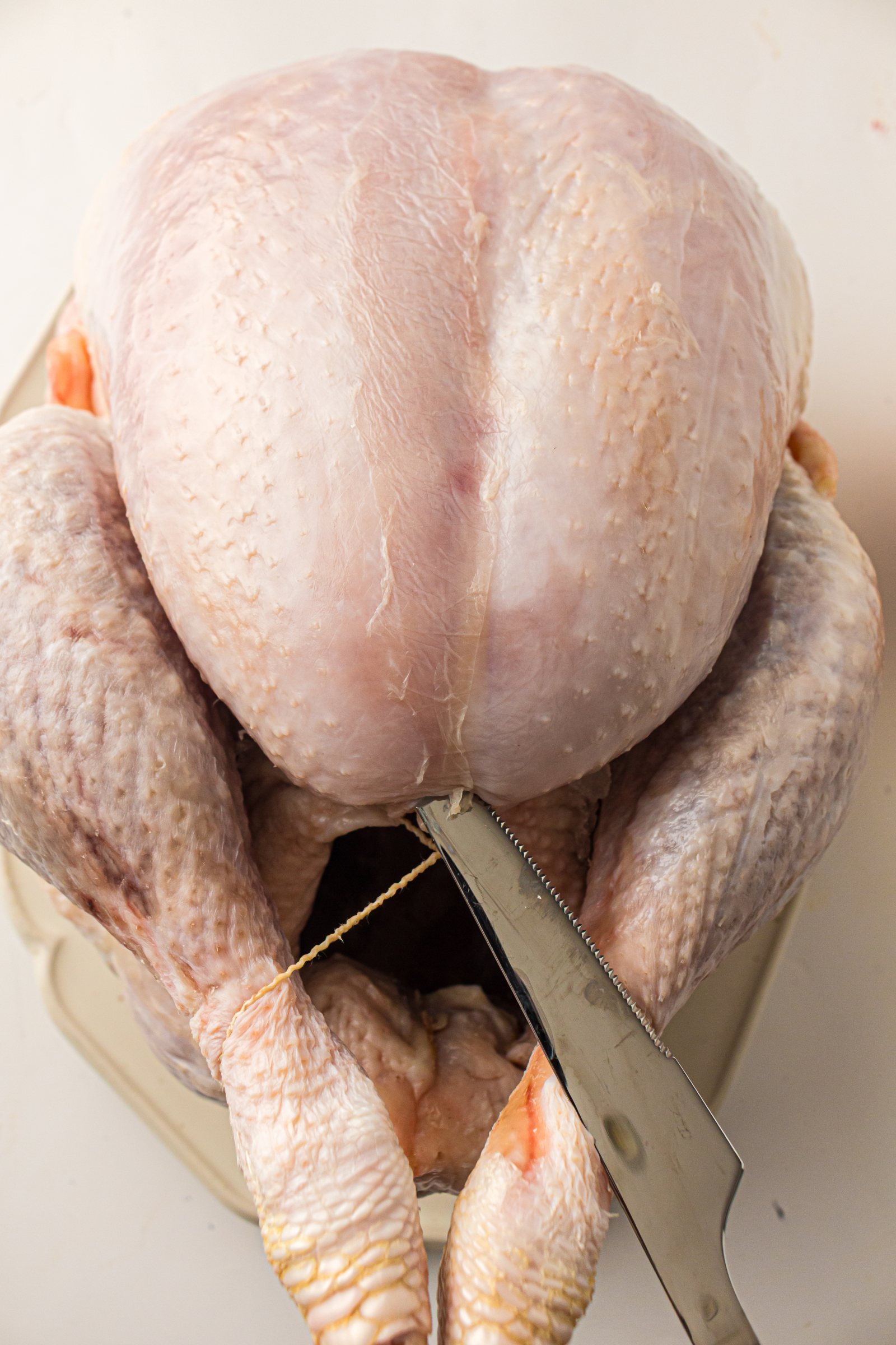 Raw whole turkey being prepped on a cutting board.