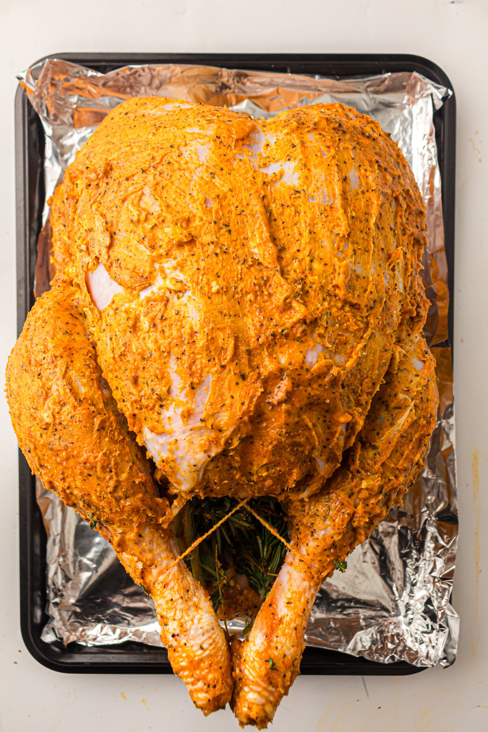 Tied buttered turkey in a roasting pan, ready for the oven.